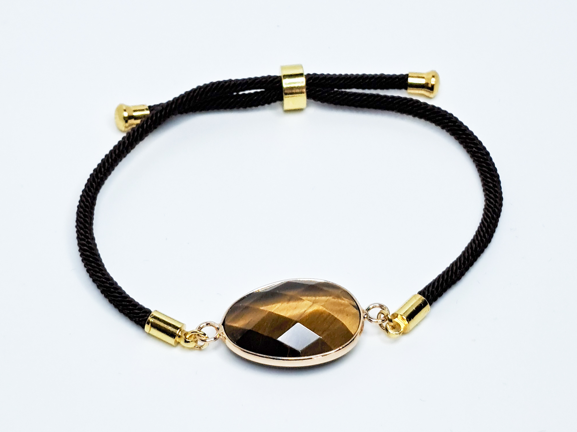 Bracelet œil-de-tigre 2 Bracelet œil-de-tigre, composé d'une seule pierre naturelle taillée, mesurant environ 2cm. Bracelet en cordon réglable noir.