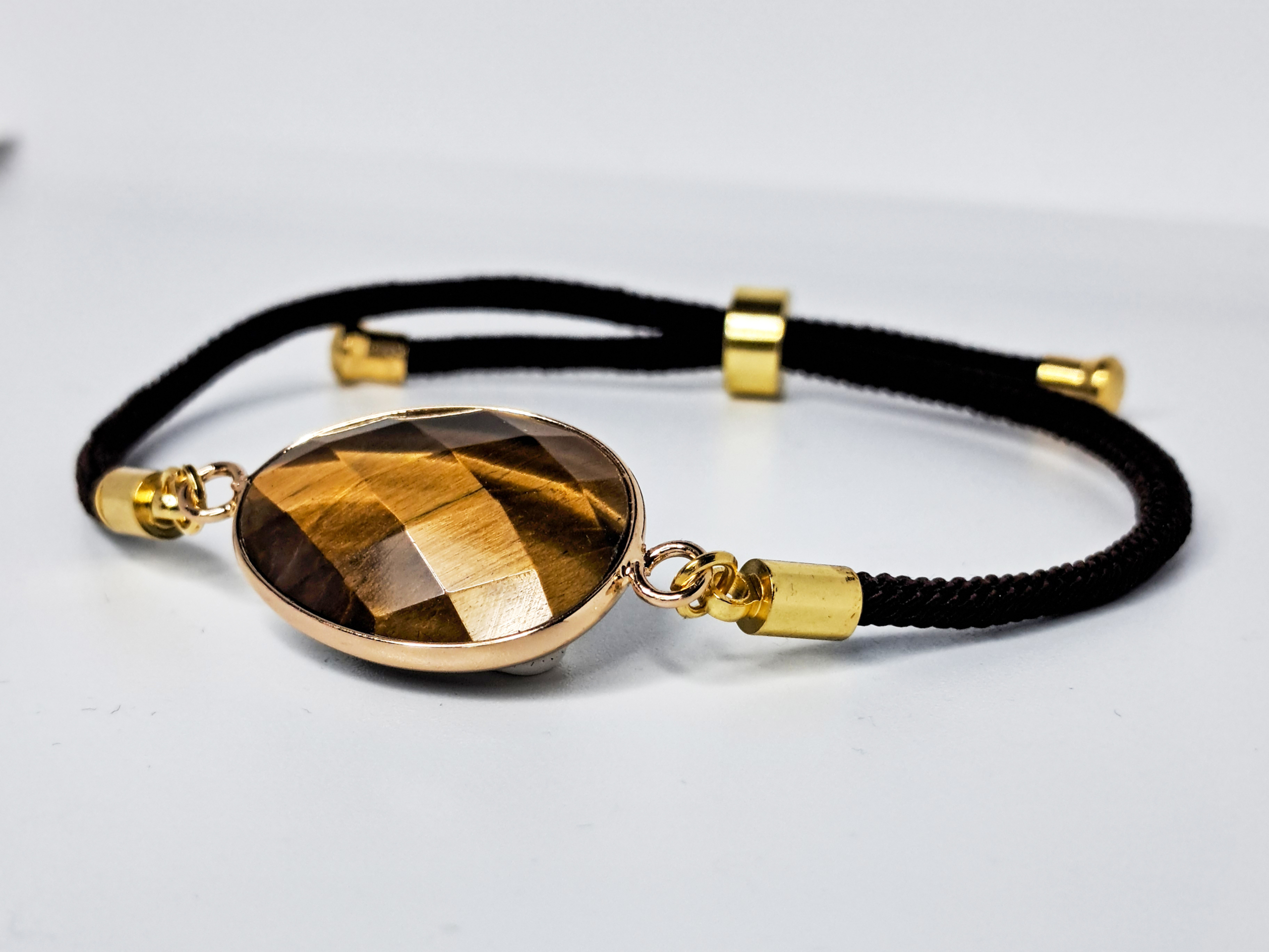 Bracelet œil-de-tigre 3 Bracelet œil-de-tigre, composé d'une seule pierre naturelle taillée, mesurant environ 2cm. Bracelet en cordon réglable noir.